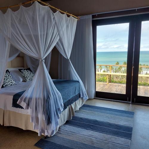 a bedroom with a bed and a view of the ocean at Coco Pontall Bangalôs in Coruripe
