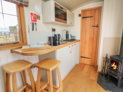 a kitchen with a stove and two stools in a tiny house at Ivy's Way in Rhayader