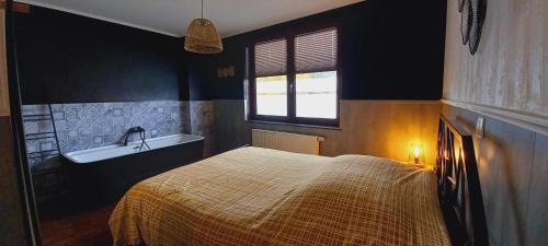 a bedroom with a bed and a bath tub at Gîte Chez Simone in Houffalize