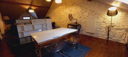 a room with a table and chairs and a stone wall at Gîte Chez Simone in Houffalize