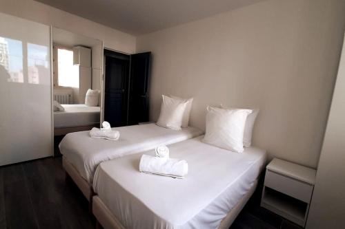 twee bedden in een hotelkamer met handdoeken erop bij Spacious Apartment in Paris Place des Fetes in Parijs