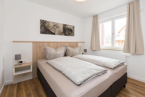 a bedroom with a bed with white sheets and a window at Haus 7 Apartment 2 Hundefreundlich in Plau am See