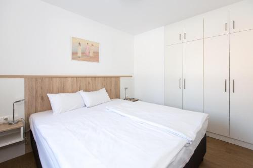 sypialnia z dużym białym łóżkiem z białymi szafkami w obiekcie Leuchtturmblick Haus 6 A 5 w mieście Plau am See
