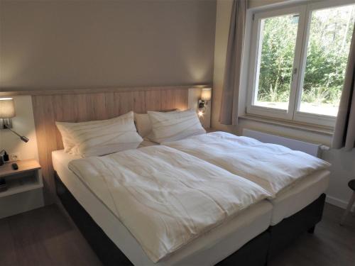 a large white bed in a bedroom with a window at Apartment PlauSeelig mit Bootsliegeplatz optional in Plau am See