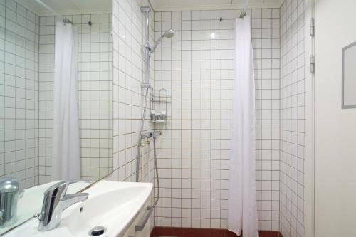 a white tiled bathroom with a sink and a shower at Spacious Scandinavian 3BR Flat in Vibrant Area in Copenhagen