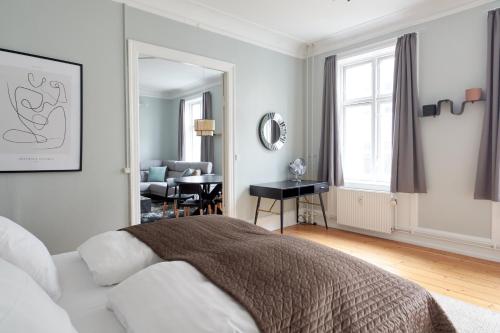 a white bedroom with a bed and a living room at Spacious Scandinavian 3BR Flat in Vibrant Area in Copenhagen