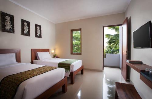 a hotel room with two beds and a television at Nesa Sanur Bali in Sanur