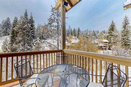 a balcony with a table and chairs and snow covered trees at Need for Speed in Donnelly