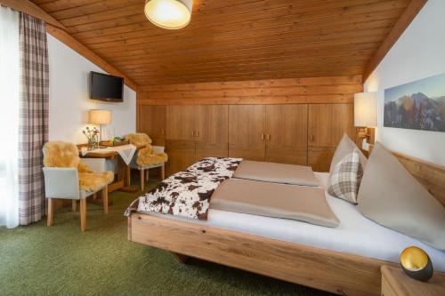 a bedroom with a bed and a table and chairs at Hotel-Pension Schattberg in Saalbach Hinterglemm