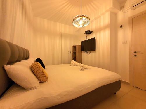 1 dormitorio con 1 cama blanca grande con lámpara de araña en Barak Royal Suites 52 garden - חמש דקות מהים ומהטיילת, en Eilat