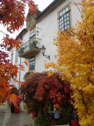 ein weißes Gebäude mit einem Balkon und Herbstblättern in der Unterkunft Hotel Monumento Pazo de Orbán in Lugo
