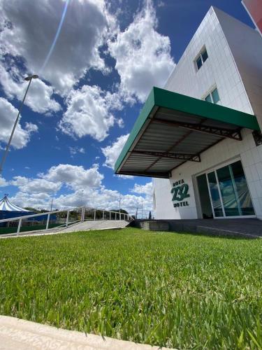 a building with a grass field in front of it at Rota 232 Hotel Caruaru in Caruaru