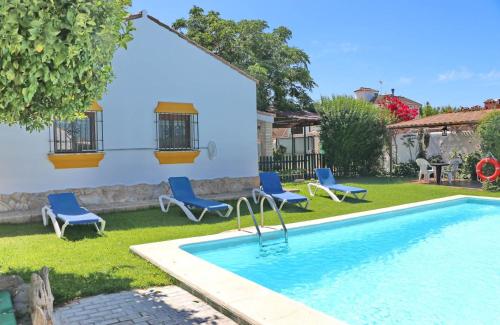 een tuin met een zwembad en stoelen en een huis bij Chalet la Dehesa in Conil de la Frontera