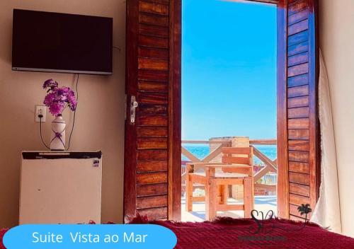 um quarto com uma televisão, um frigorífico e uma janela em Pousada Sunrise Beach em Cumbuco