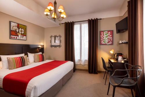パリにあるシャティヨン パリ モンパルナスのベッド、テーブル、椅子が備わるホテルルームです。