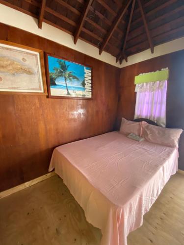 Un pequeño dormitorio con una cama rosa en una habitación en Westport Cottage, en Negril