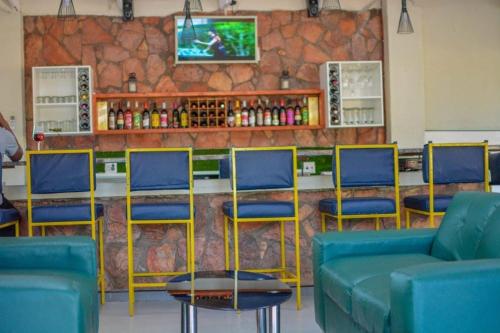 a bar with blue chairs and a counter with a tv at Lamamie guest house in Thohoyandou