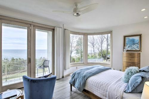 a bedroom with large windows and a bed and a chair at Grand Egg Harbor Home with Stunning Lake Views! in Egg Harbor