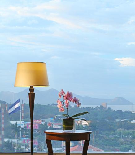 a table with a lamp and a vase with flowers on it at Real Intercontinental Metrocentro Managua by IHG in Managua