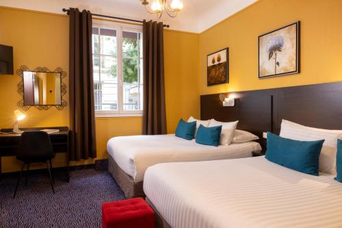 una camera d'albergo con due letti e una finestra di Chatillon Paris Montparnasse a Parigi