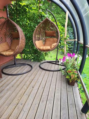 two wicker chairs sitting on a wooden deck with flowers at Vēverkalni in Vidriži