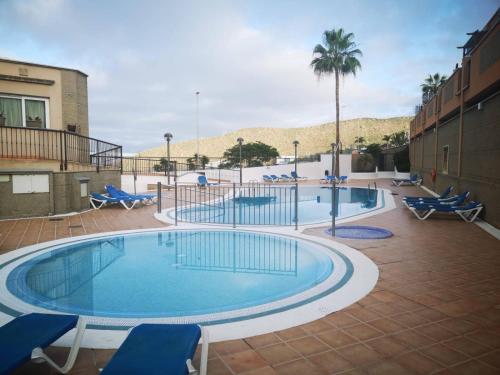 a large swimming pool with chairs and a palm tree at 2-bed AMAZING OCEAN VIEW APARTMENT Costa Adeje in Adeje