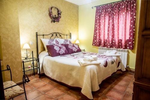 a bedroom with a large bed with pink curtains at Apartamentos Cruz Mar in Poveda de la Sierra