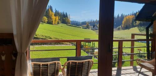 a balcony with chairs and a view of a green field at Babcia Góralka house in Bukowina Tatrzańska