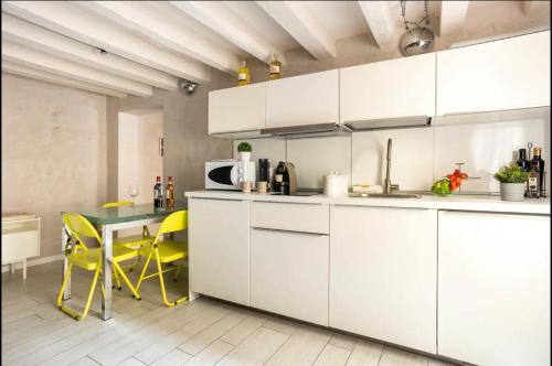 une cuisine avec des placards blancs et une table avec des chaises jaunes dans l'établissement MMeSuite Arena di Verona by Maisonme Collection, à Vérone