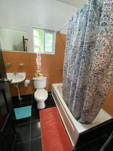 a bathroom with a toilet and a shower curtain at Westport Cottage in Negril