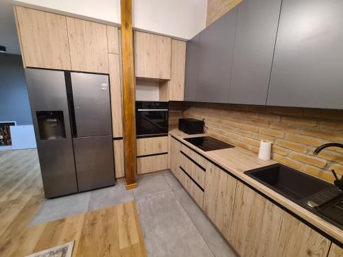 a kitchen with stainless steel appliances and wooden cabinets at Apartamenty Osmolice w Stawach in Dęblin
