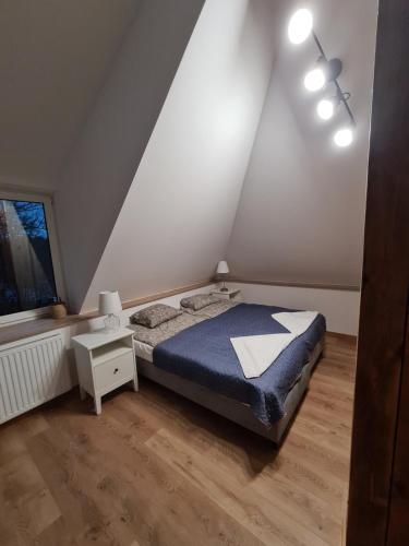 a bedroom with a bed and a nightstand and a window at Apartamenty Osmolice w Stawach in Dęblin