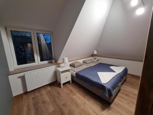 a small bedroom with a bed and two windows at Apartamenty Osmolice w Stawach in Dęblin
