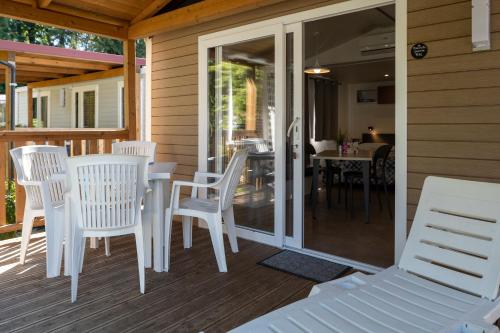 a patio with white chairs and a table on a porch at Camping Eden Glamping in Dormelletto