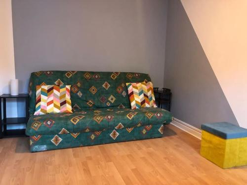 a green couch with colorful pillows in a living room at Appartement Lumineux et Rénové dans les Pyrénées in Eaux-Bonnes