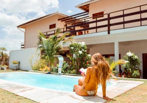 a woman in a yellow bikini sitting next to a swimming pool at Casa Naná - Suites in Prea
