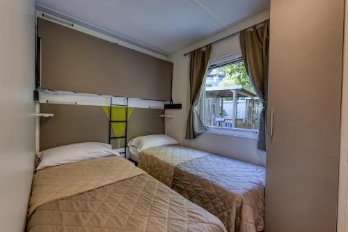 two beds in a small room with a window at Camping Eden Glamping in Dormelletto