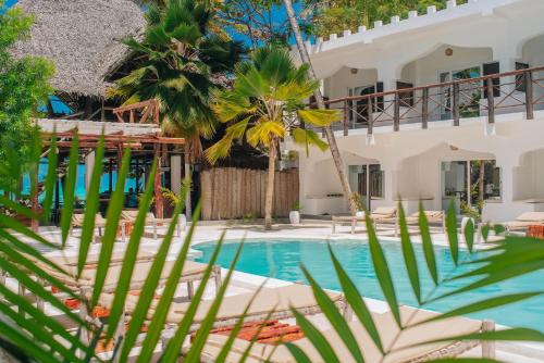 a villa with a swimming pool and palm trees at Dhow Resort in Jambiani