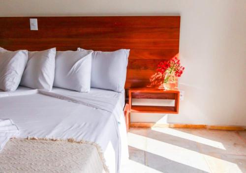 1 dormitorio con cama blanca y cabecero de madera en Pousada Naná, en Prea