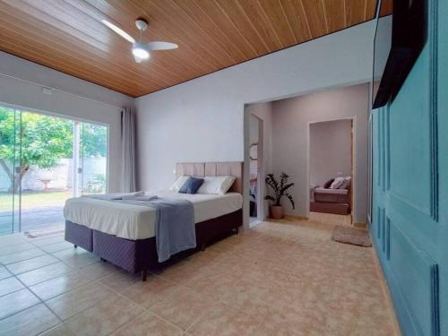 Schlafzimmer mit einem Bett und einer Glasschiebetür in der Unterkunft Casa agradável com jacuzzi, área de lazer, enxoval in Andradina