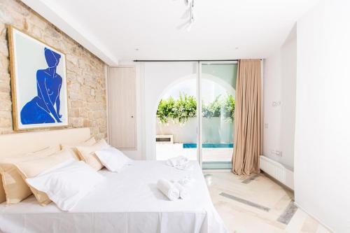 1 dormitorio con cama blanca y ventana grande en Duplex avec piscine Détente et élégance, en Gammarth