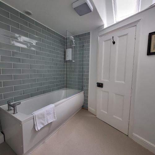 a bathroom with a white tub and green tiles at Chapter House YORK in York