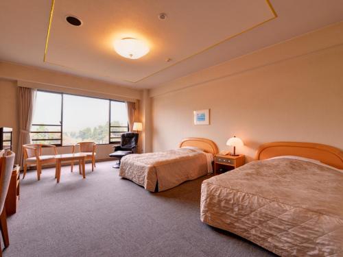 a hotel room with two beds and a table and chairs at Yufuin Sansuikan in Yufuin