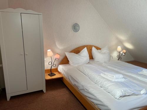 a bedroom with a white bed with two lamps at Haus Merian in Winterberg