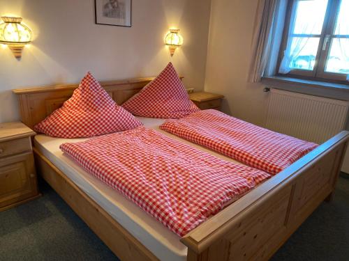 Una cama con almohadas rojas y blancas. en Landhaus-Bierling, en Bad Kohlgrub