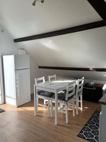 La cuisine est équipée d'une table et de chaises blanches. dans l'établissement Appartement coquet dans maison individuelle, à Lisses