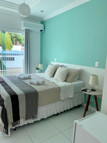 a white bedroom with a large bed and a window at Hotel The Green Ecologic in Guarujá