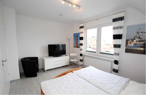 a bedroom with a bed and a tv and a window at Neuwerk in Cuxhaven