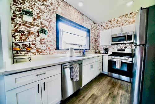 a kitchen with white cabinets and a brick wall at Downtown Boho Revival Home PNW in Albany