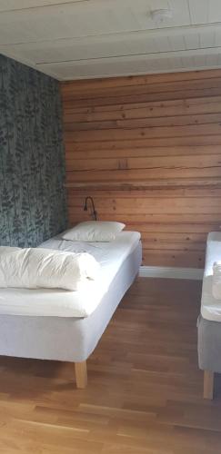 a bedroom with two beds and a wooden wall at Ammeråns Fiskecamp in Hammarstrand